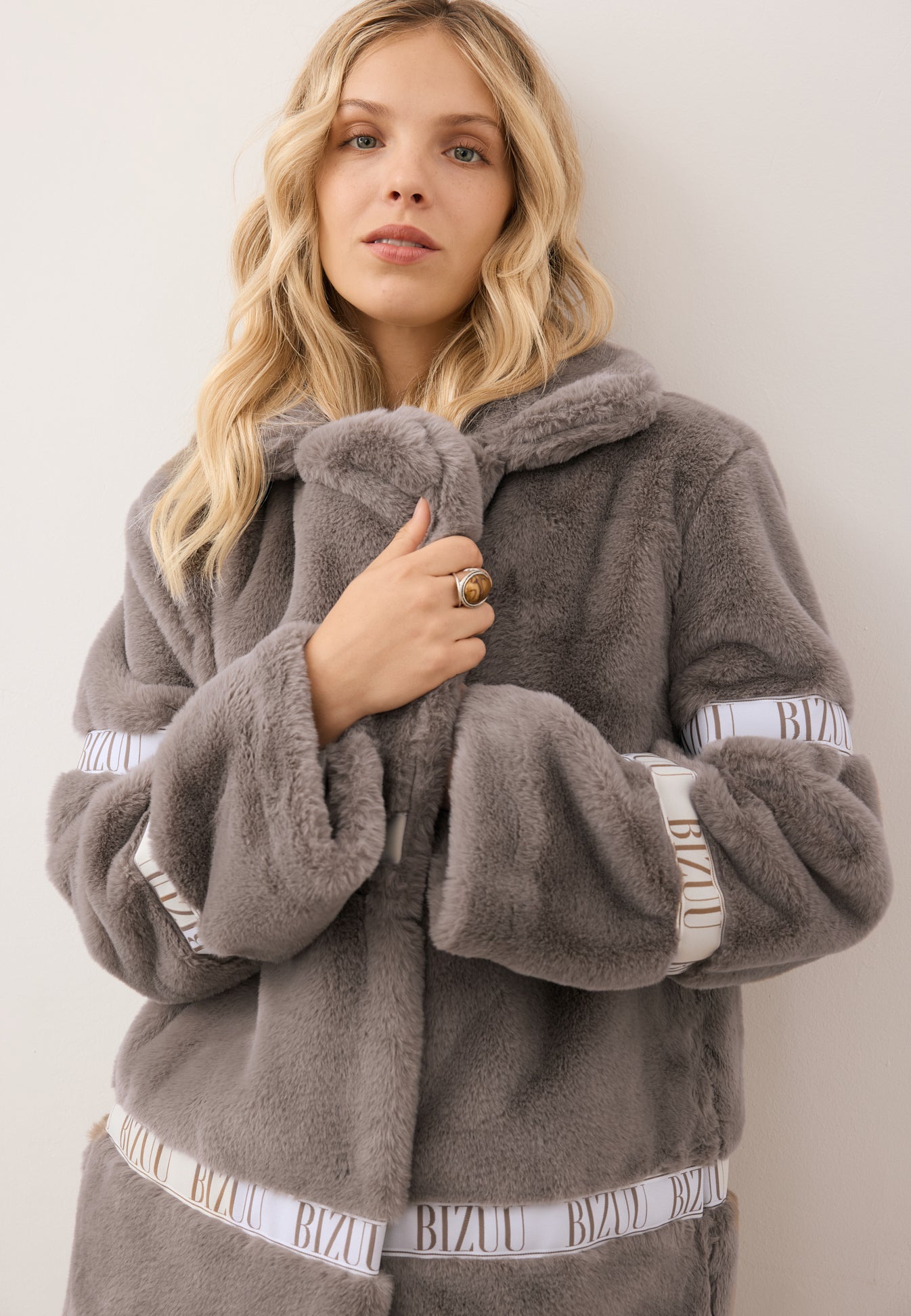 Zbliżenie na modelkę opatulającą się kołnierzem futra FLORENCE w kolorze taupe.