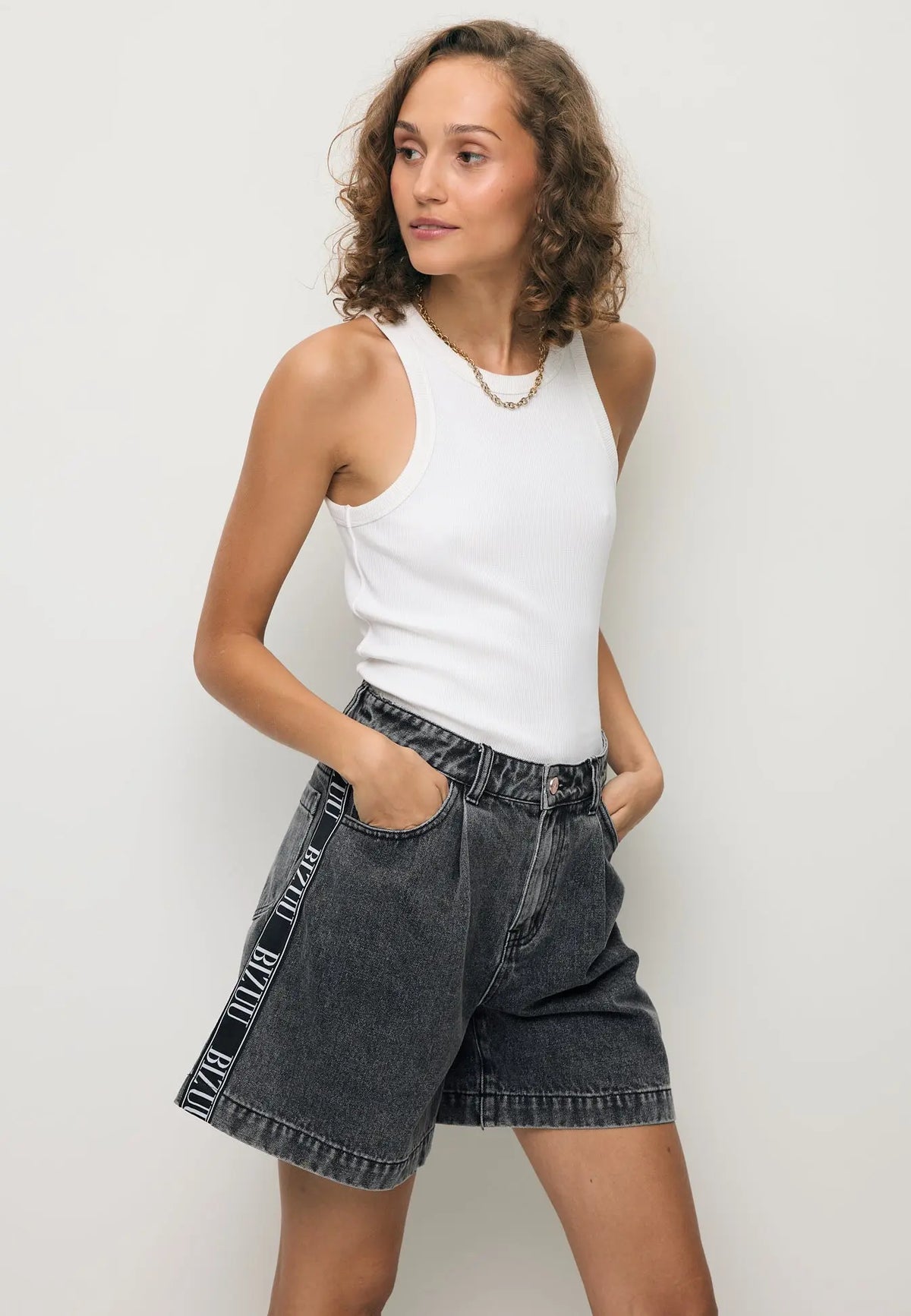 Modelka ubrana w czarne jeansowe shorty z logowaną taśmą z boku MIREYA.