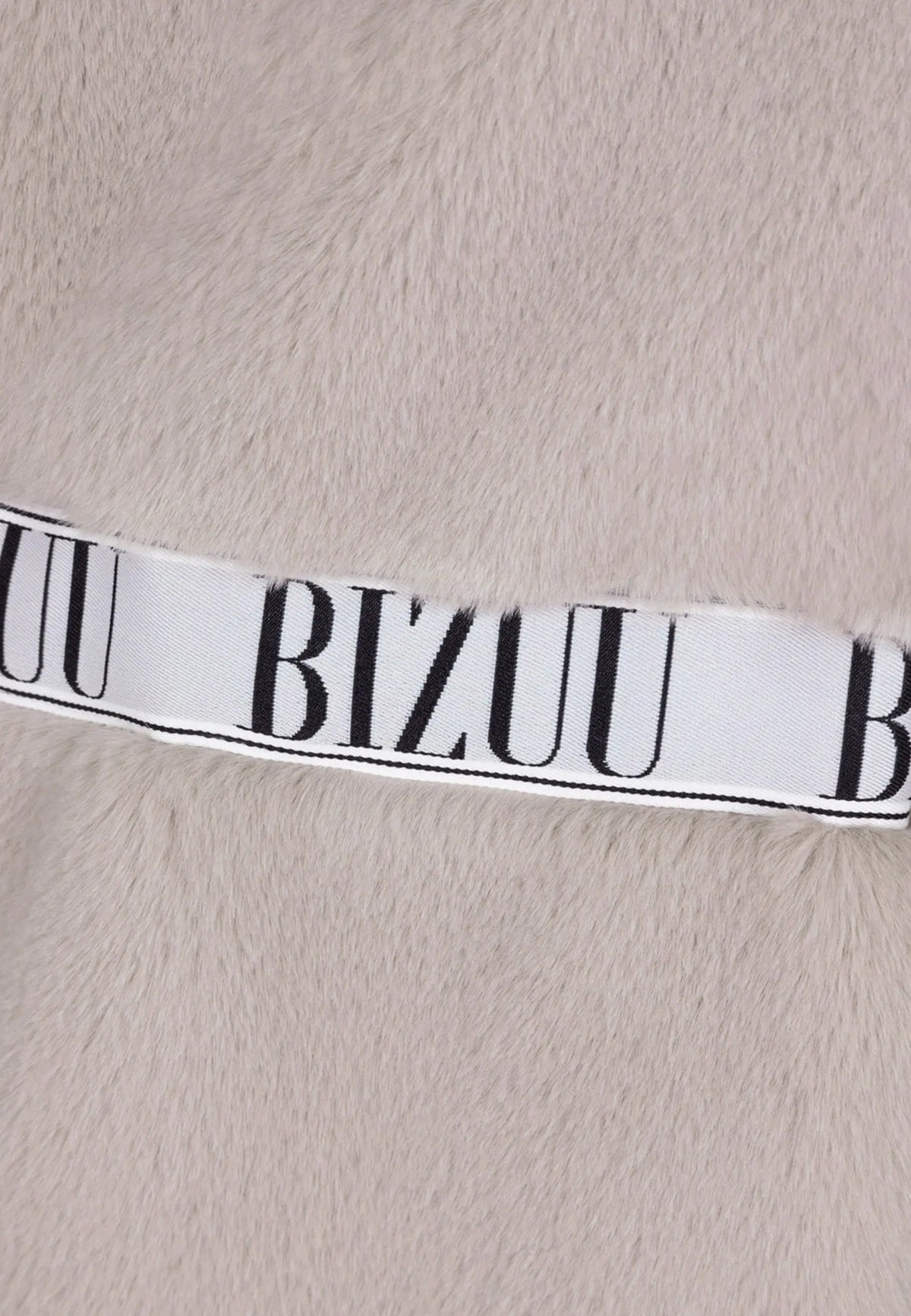 Zbliżenie na logo Bizuu na beżowym futrze FLORENCE.